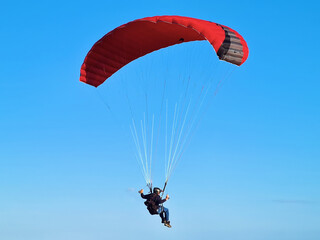 Man paragliding on Santinho beach in Florianópolis, Santa Catarina, mountainous coastal landscape, flight and adventure on the sand on a sunny day with blue skies