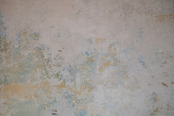 Weathered wall surface displaying an abstract blend of textures, with faded paint in warm-toned and pastel hues. The visual evokes a rustic and timeless artistic impression found in aged, natural elem
