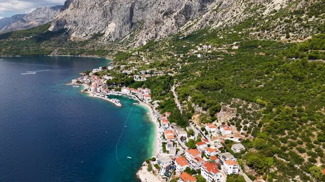 Spectacular aerial drone footage of coastal settlement near Drasnice village beneath majestic Biokovo mountains with crystal clear Adriatic waters