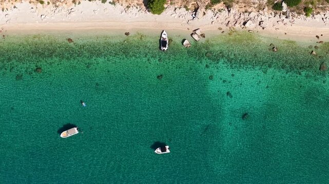 Garma Beach Podgora Croatia top down turquoise lagoon pebble shore anchored boats and rocky shoreline under summer sun