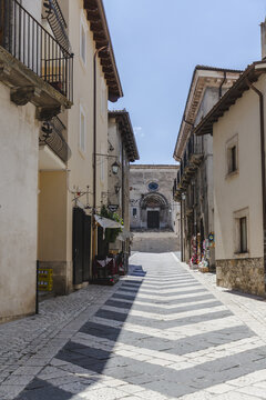 View of an inviting cobblestone street paved with a striking black and white chevron pattern, leading to a church in Pescocostanzo, Abruzzo, Italy.