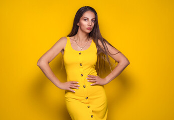 Obraz premium Gorgeous young woman posing, isolated on yellow background. Beautiful young adult lady posing while standing dressed in summer dress. Pretty girl.