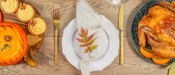 Festive Thanksgiving dinner table with pumpkin soup, mini pies, roasted chicken, and autumn decorations, top view, free space for text