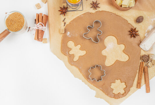 Gingerbread cookie dough with cutters, spices, and ingredients on kitchen table, top view, free space for text