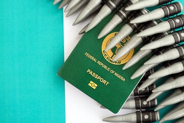 Nigerian passport and rifle bullets on flag. The concept of warfare and gun selling