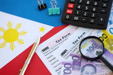 Philippines peso money bills and calculator with tax form on flag. Taxation and accounting concept