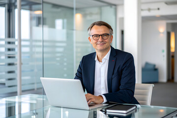 Fototapeta premium Mature businessman working on laptop in office