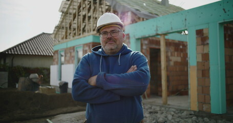 Construction worker with arms crossed at building site, confident and proud industry professional,...