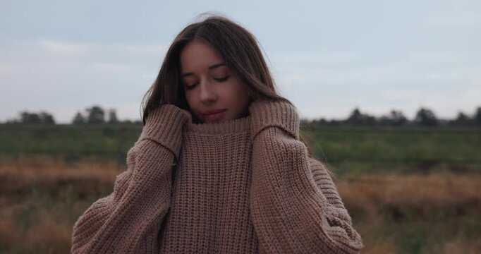 A young woman wrapping herself in a sweater in early autumn
