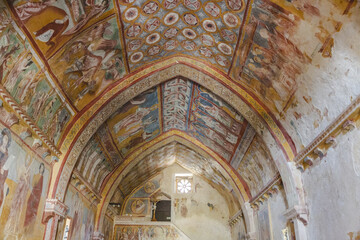 View of vibrant frescoes adorning the arched ceiling of a medieval church, a symphony of color and history whispering tales of devotion, Bominaco, Abruzzo, Italy.