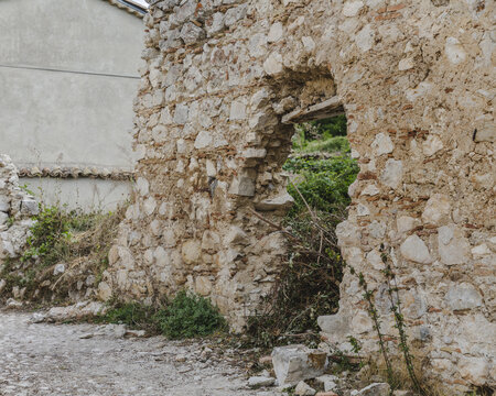 View of weathered stone walls reveal glimpses of verdant growth within a crumbling structure in Frattura Vecchia, Abruzzo, Italy.