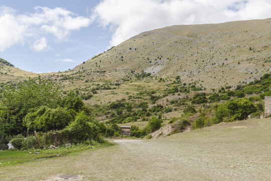 View of rugged terrain under a cloudy sky with a dirt road leading into the distance, where mountain meets the sky, Frattura Vecchia, Abruzzo, Italy.