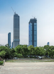 Fototapeta premium Striking Urban Skyline with Modern Skyscrapers Under Construction Amidst Lush Greenery