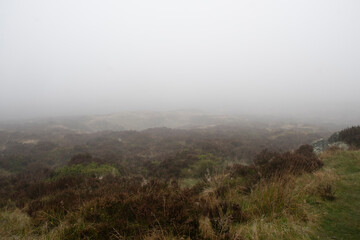 Mist descends and obscures the landscape on a foggy day in the Peak District
