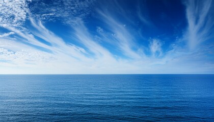 Obraz premium Vast Ocean Horizon On Dramatic Blue Sky With Wispy Clouds