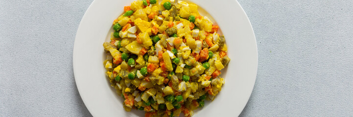 This dish features a vibrant salad composed of boiled eggs, tender chicken breast, diced potatoes, sweet carrots, and fresh green peas, all topped with a drizzle of olive oil for flavor, banner