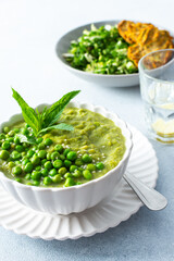 Creamy green pea and broccoli soup garnished with fresh peas is paired with crispy zucchini pancakes and a vibrant salad, creating a healthy and delightful meal