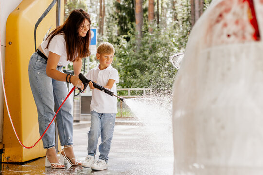 Mother and son washing car together with high pressure washer at outdoor self-service car wash on summer day, family activity and bonding time   - Powered by Adobe