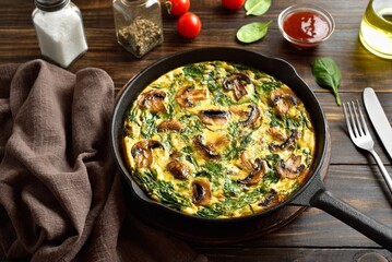 Frittata with spinach and champignon mushrooms in cast iron skillet