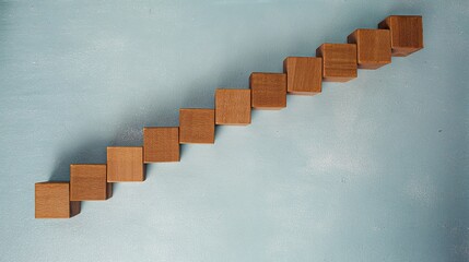 Wooden blocks in staircase formation on blue, minimalist composition symbolizing growth and progress