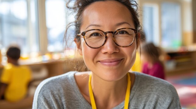 Asian woman smiling at camera in library or classroom setting.