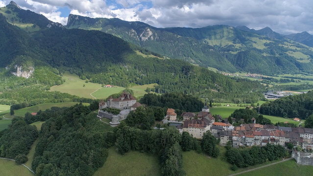 Aerial view of the medieval Gruy&Atilde;&uml;res Castle standing proudly atop a verdant hill, contrasting against the majestic backdrop of the Swiss Alps, Gruy&Atilde;&uml;res, Fribourg, Switzerland.