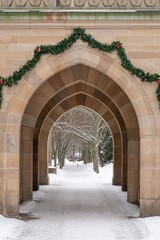 Fototapeta premium Snow covered historic stone arch with minimal festive garland decoration
