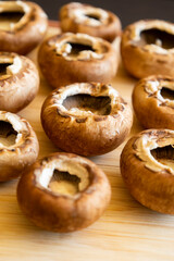 fresh champignon mushrooms on wooden cutting board close up