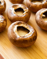 fresh champignon mushrooms on wooden cutting board close up