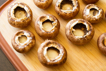 fresh champignon mushrooms on wooden cutting board close up