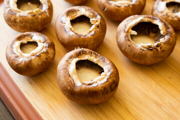 fresh champignon mushrooms on wooden cutting board close up