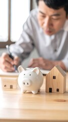 Focused man planning finances with piggy bank and house models