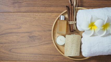 Spa background with rolled white towel, frangipani flower, natural loofah, essential oil bottle,...