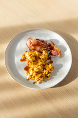A plate of bacon and scrambled eggs.
