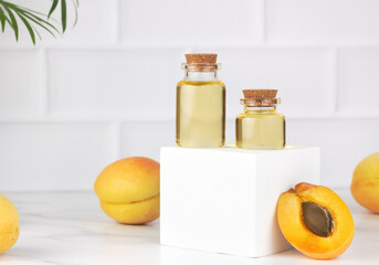 Apricot oil in glass bottles with fresh apricots on white background. Natural skincare, aromatherapy concept. Copy space