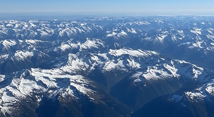 Fototapeta premium Aerial view of snow-covered mountain ranges under clear blue sky