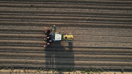 Aerial View of a Tractor Planting Seeds in a Large Agricultural Field During a Sunny Day Showcasing Modern Farming Techniques and Rural Landscapes