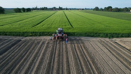 Aerial view of a family and friends gathered with a tractor in a freshly plowed field ready for planting a bountiful harvest