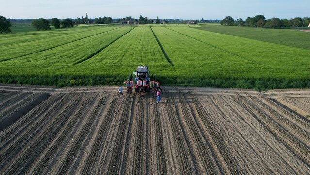 Aerial view of a family and friends gathered with a tractor in a freshly plowed field ready for planting a bountiful harvest