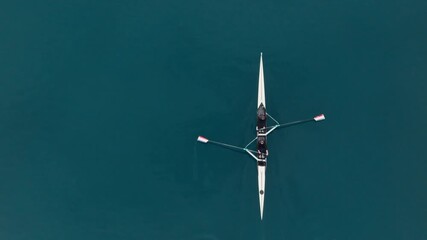 Two athletes rowing a sculling boat on calm blue water, teamwork and endurance in competitive sport. Rowers are practicing sport rowing. Rowers in a racing boat row in slow motion video 120fps. - Powered by Adobe