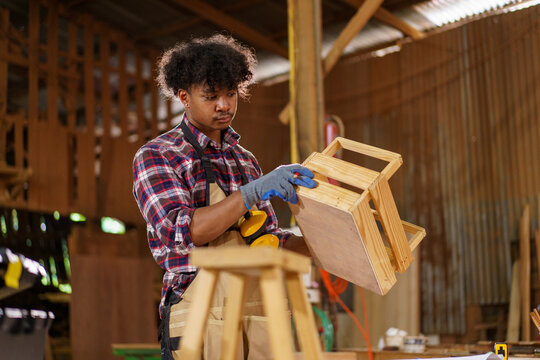 Black carpenter working with wood design plans in workshop - Powered by Adobe