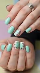 Mint green nails adorned with delicate floral designs, showcasing a soft and feminine aesthetic.