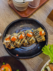 Front view Delicious and delicious. A plate of delicious fried sushi rolls consisting of fish eggs and mayonnaise on a black plate.