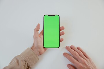 Hand Holding Smartphone with Green Screen, POV mockup for app or website display on white background.
