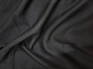 Fototapeta premium Textured black fabric with subtle geometric pattern and draping folds
