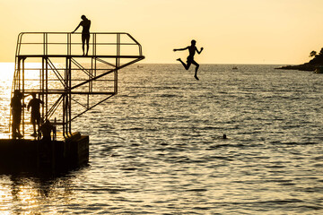 Silhouetten beim Sprung ins Meer vom 3 Meter Turm