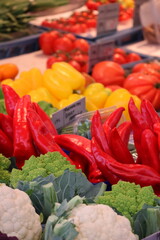 Market stall with cauliflower, romanesco, red and yellow peppers and tomatoes – fresh vegetables display