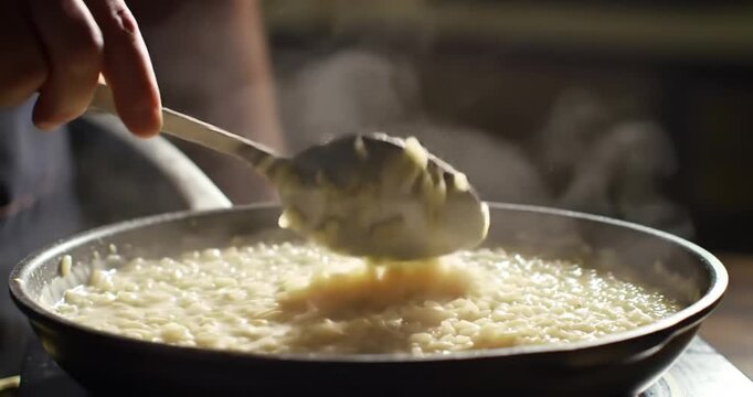 Cooking creamy risotto in a kitchen with steam rising