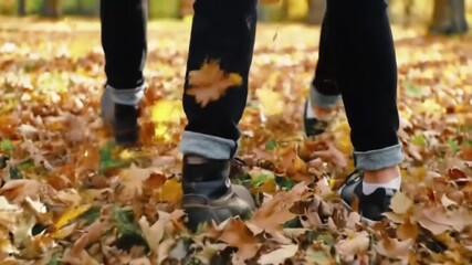 A low-angle, close-up shot of a person's feet walking through a thick carpet of colorful fallen autumn leaves. This clip captures the crisp, peaceful feeling of a walk in the woods during the fall sea