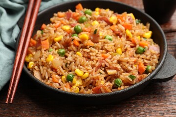 Delicious fried rice in baking dish served on wooden table, closeup